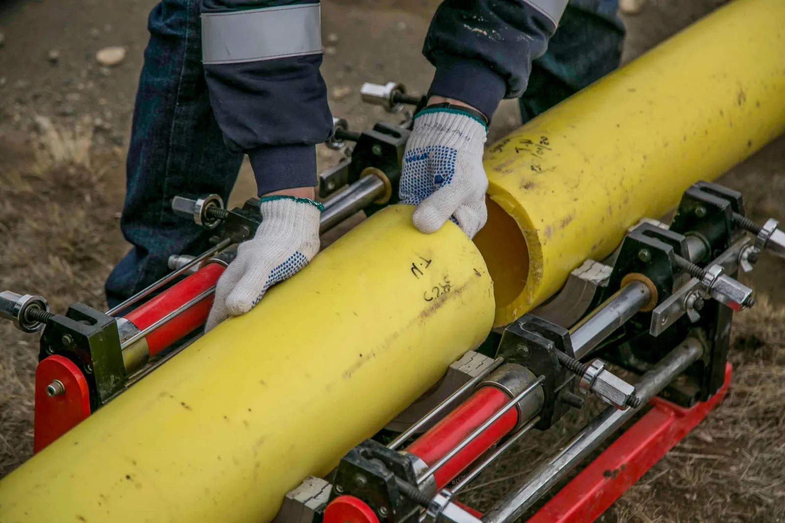 Mains gantées assemblant deux canalisations jaunes